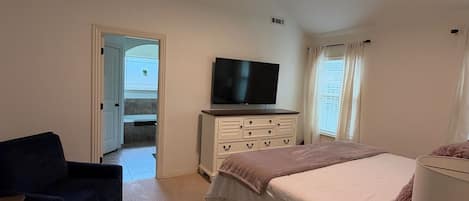 A hotel room with a bed, a TV, a ceiling fan, a desk, and a chair.