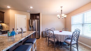 A kitchen with a granite countertop, stainless steel appliances, and a dining area with a table and chairs. - Bikers Paradise , Trails, Promenade Mall, AMP, Restaurants, and Top Golf (Rogers)