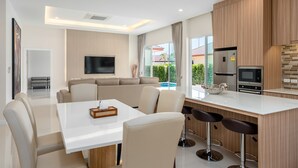 Een moderne keuken met een eethoek, een flatscreen televisie en uitzicht op een zwembad.