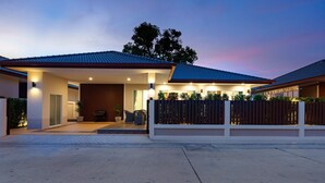 Een modern huis met een overdekte veranda, een barbecue en een hekwerk.