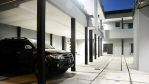 Un estacionamiento techado con un coche estacionado bajo un toldo blanco.