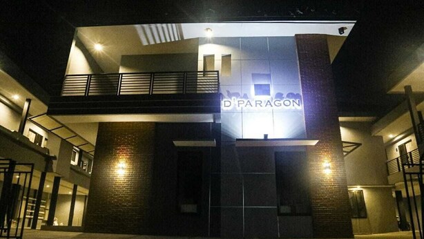 Un edificio con un letrero que dice "D'PARAGON" en la entrada, que presenta un diseño arquitectónico moderno con un balcón y una escalera.