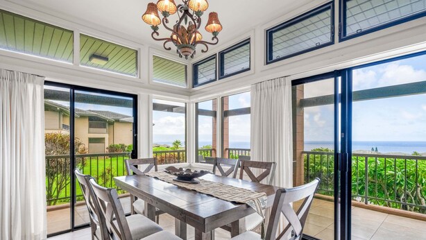Un comedor con una mesa y sillas, ventanas amplias y vista al mar.