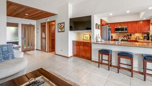 Una cocina moderna con armarios de madera, una isla grande con taburetes de bar y un televisor de pantalla plana.