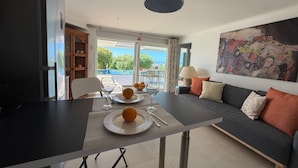 Un salon moderne comprenant un coin repas, un canapé, un tableau et une vue sur l’extérieur.