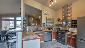 A modern kitchen with a central island, stainless steel appliances, and a herringbone-patterned backsplash.