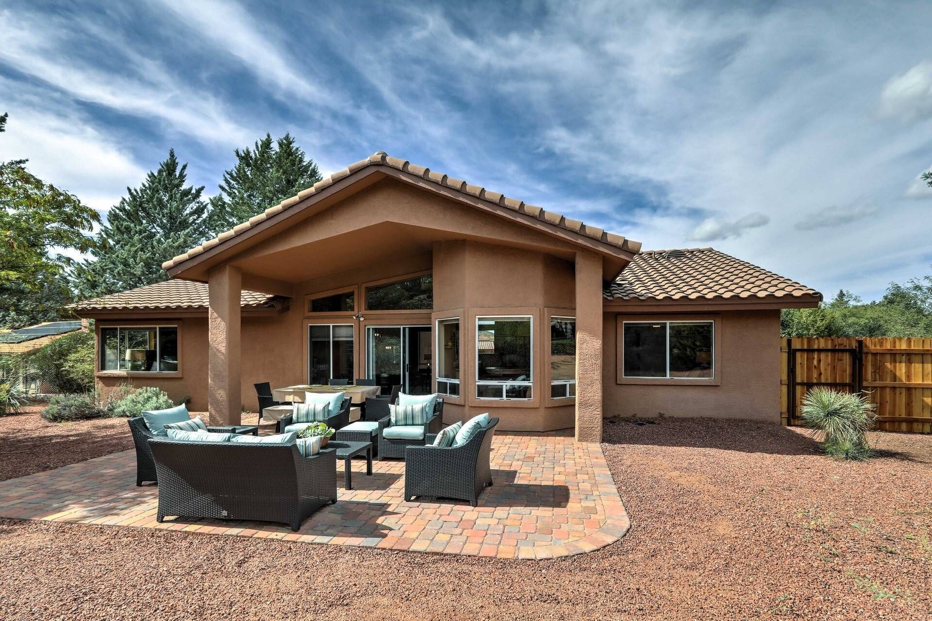 A house with a covered patio area, large windows, and a fenced yard.