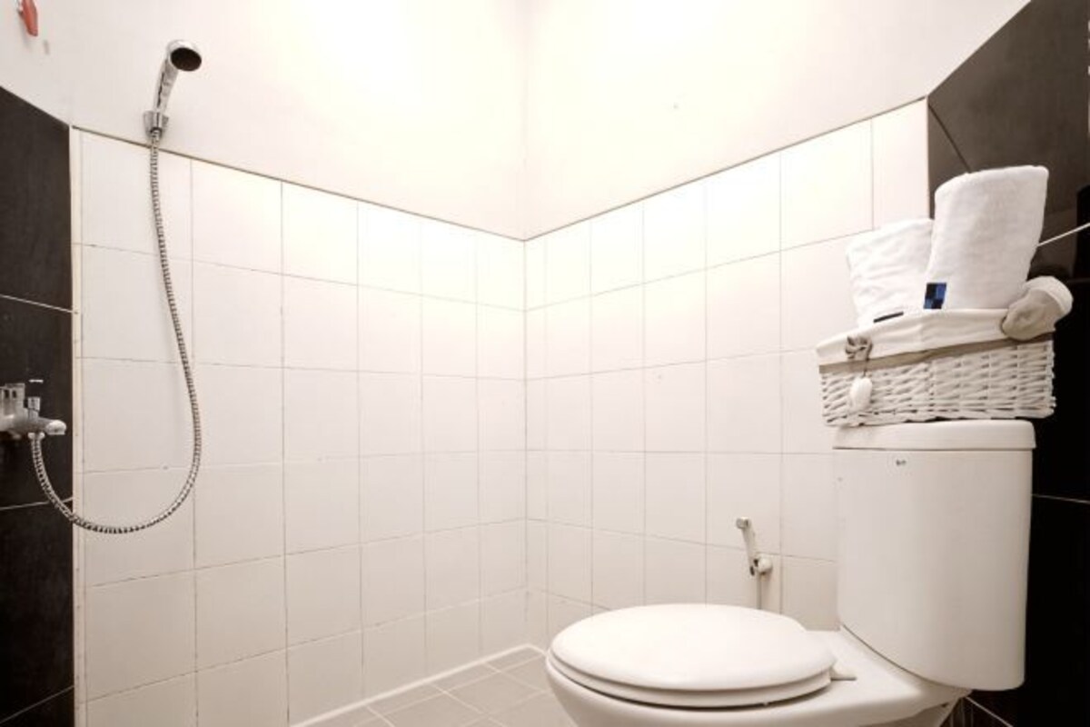 A bathroom with a white toilet, a shower, and a towel rack with towels.