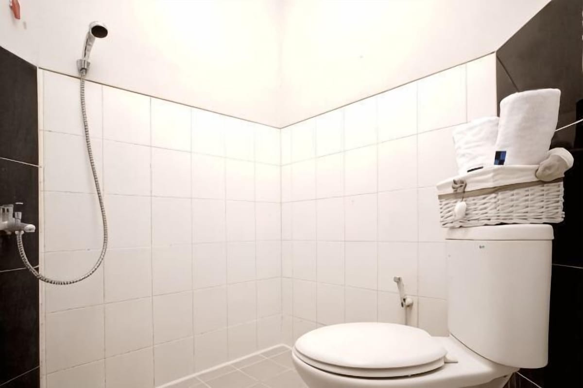 A bathroom with a white toilet, a shower, and a towel rack with towels.