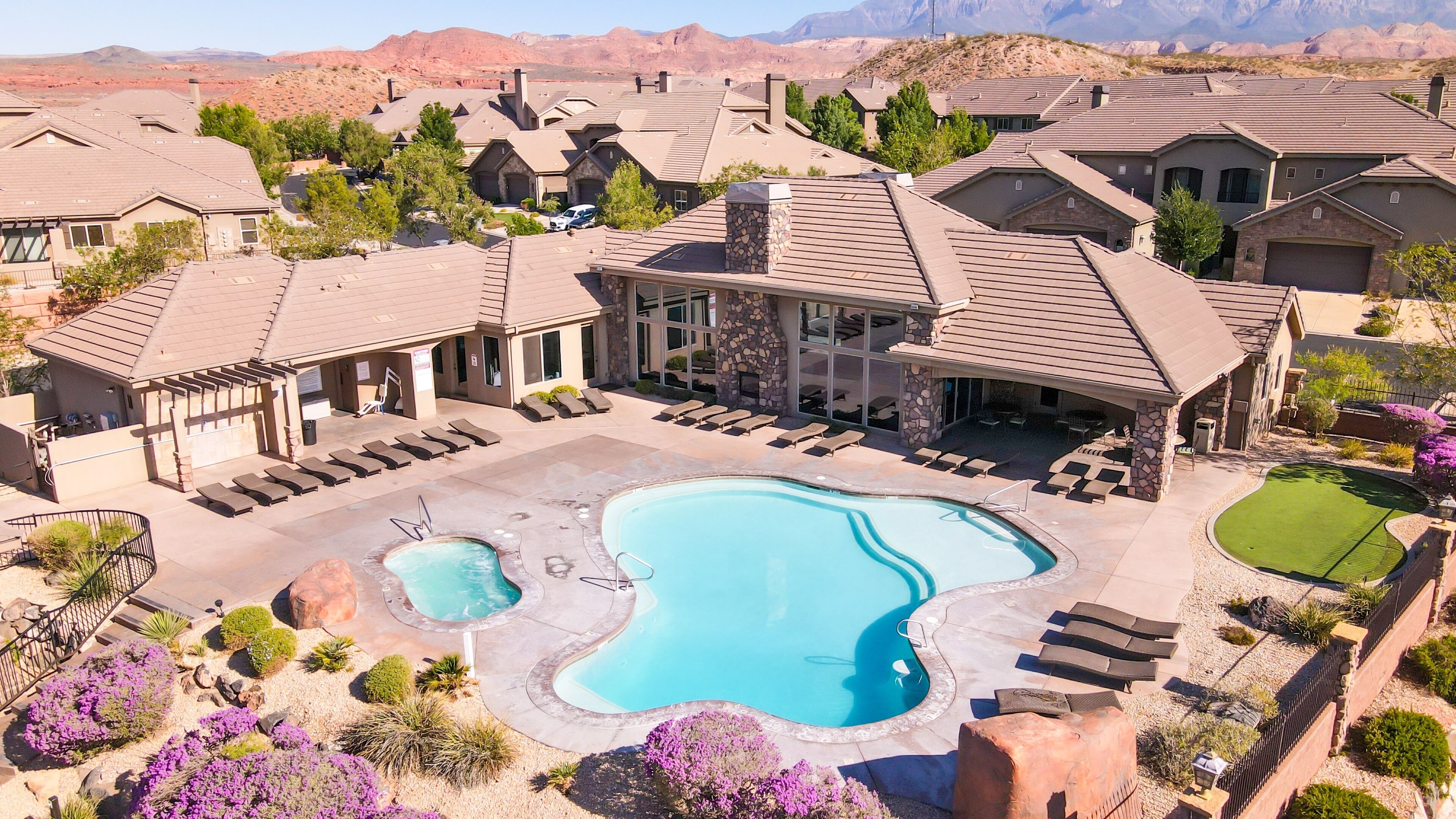 A residential area with a large swimming pool, multiple houses, and a mountain backdrop.