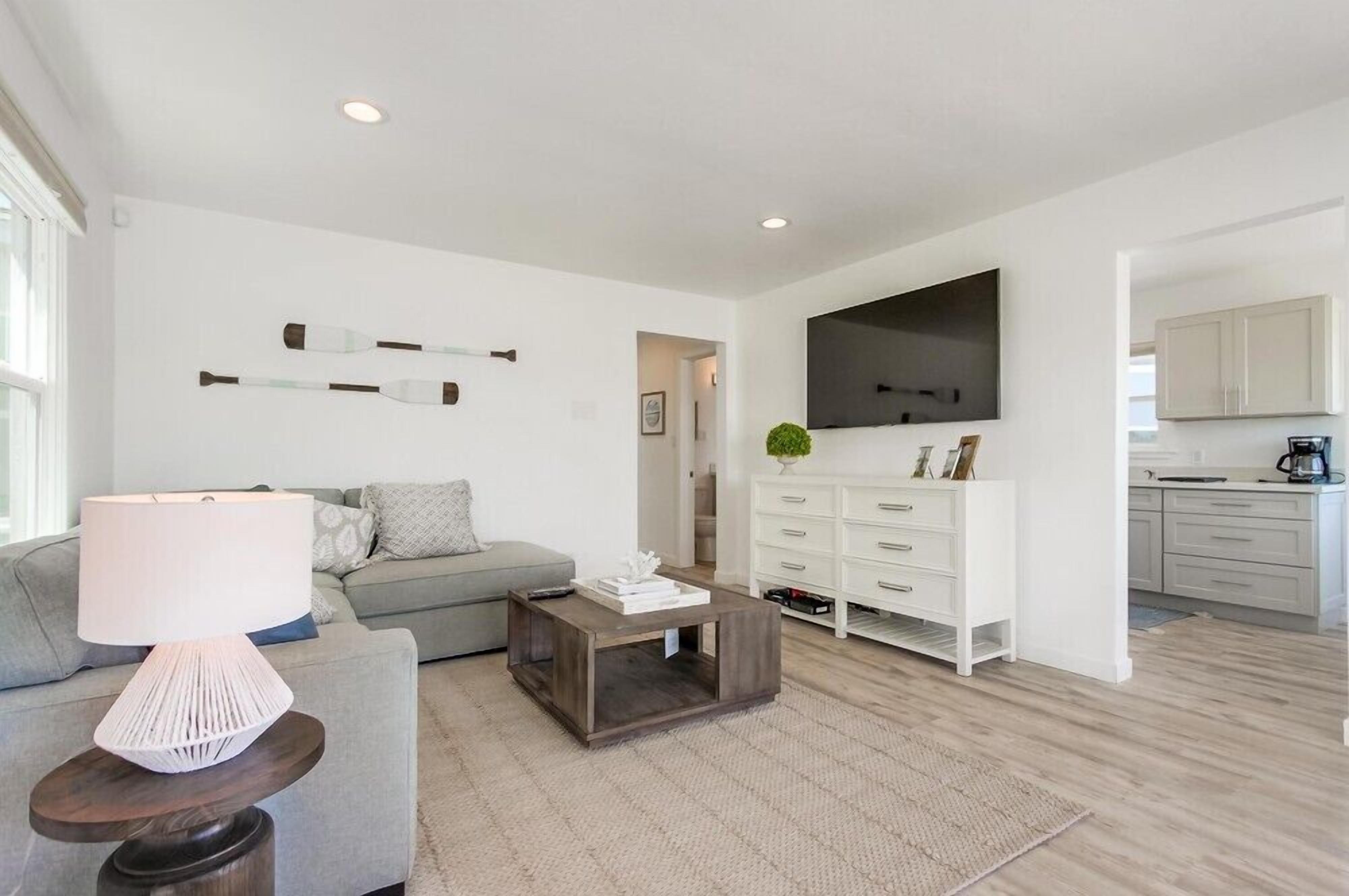 A modern living room with a grey sofa, a coffee table, and a TV mounted on the wall.