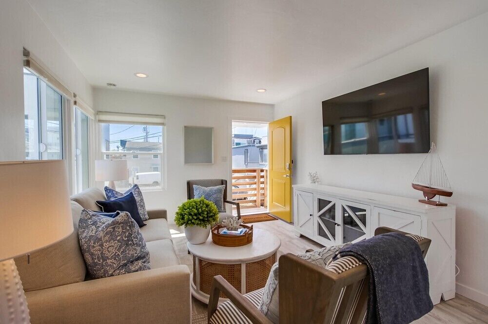 A modern living room with a sofa, armchairs, a coffee table, and a television mounted on the wall.