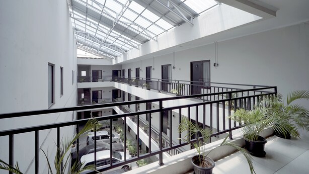 Een meerlaags interieur met een glazen dak, balkons en potplanten.