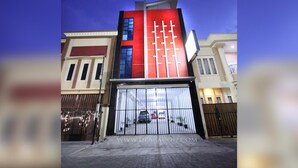 Een modern gebouw met een rode gevel en een grote garagepoort.