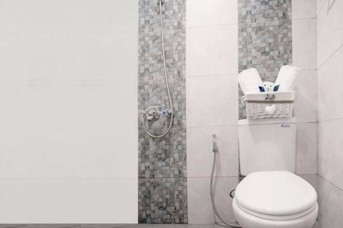 A bathroom with a shower, toilet, and a towel rack.