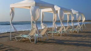 Une plage avec des parasols blancs et des chaises longues.