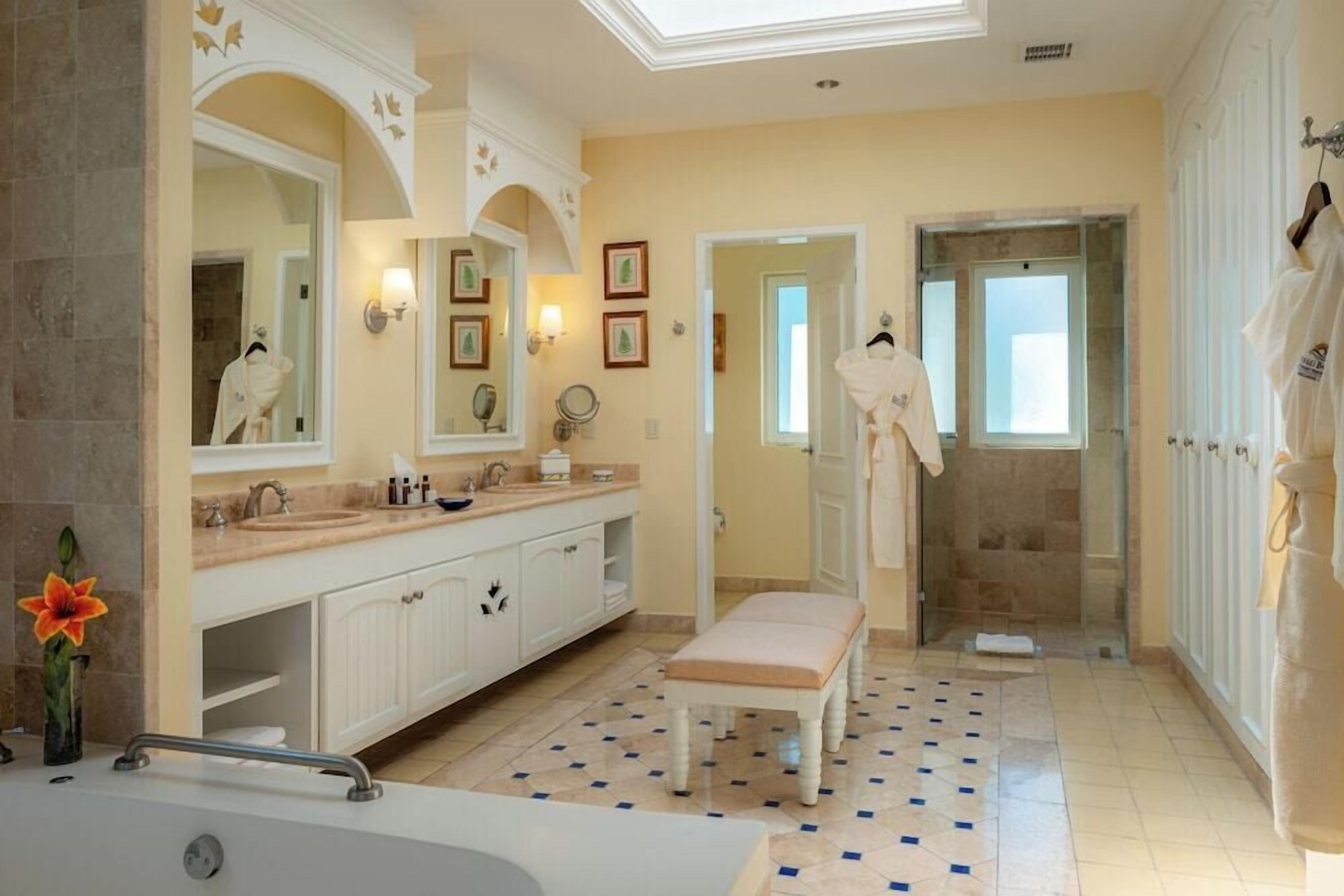Un baño con bañera, lavamanos, un banco y zona de ducha.