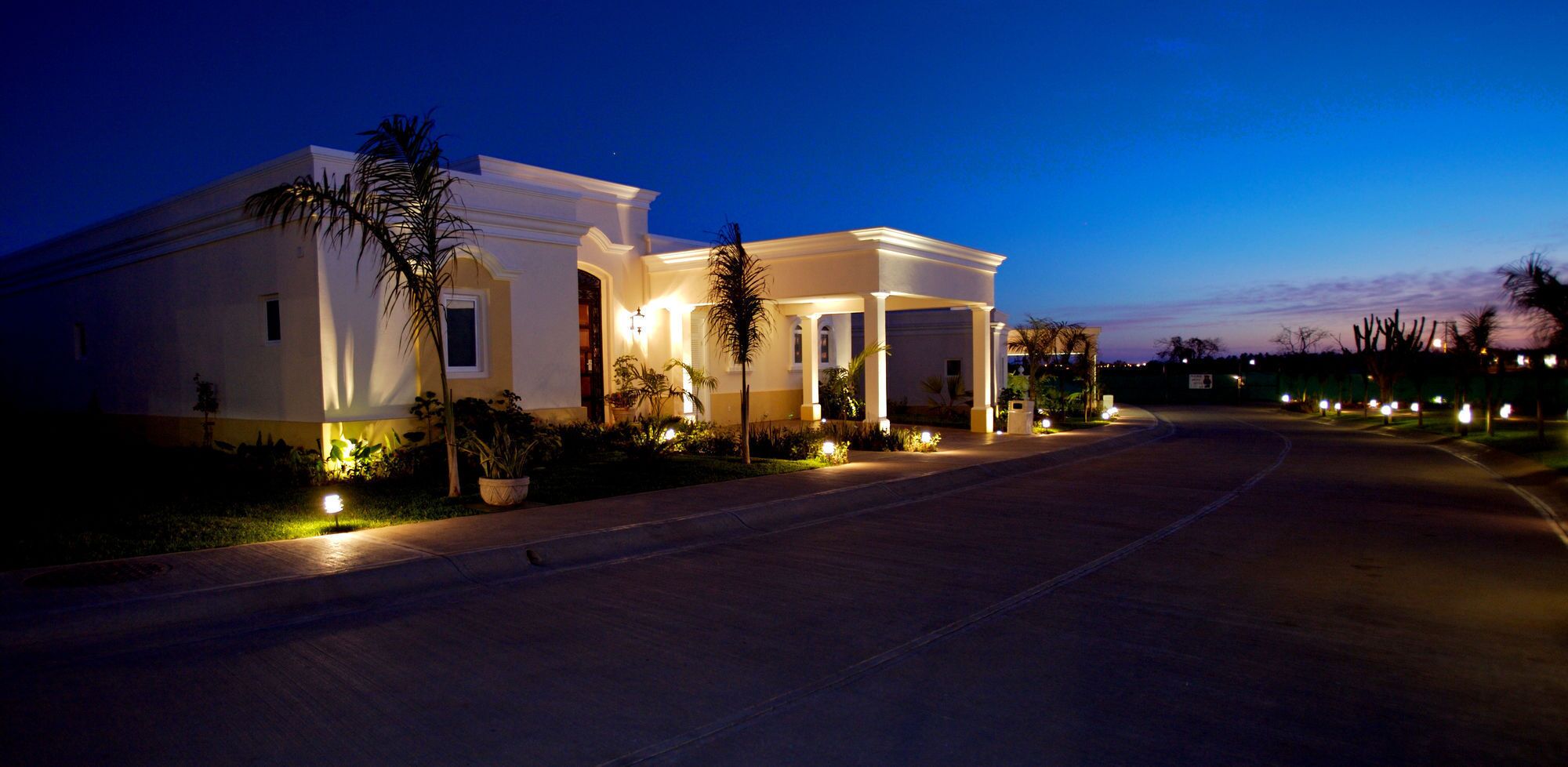 A large, modern house with a driveway and well-lit exterior.