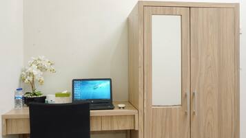 A room with a wooden desk, a laptop, a chair, and a wardrobe.