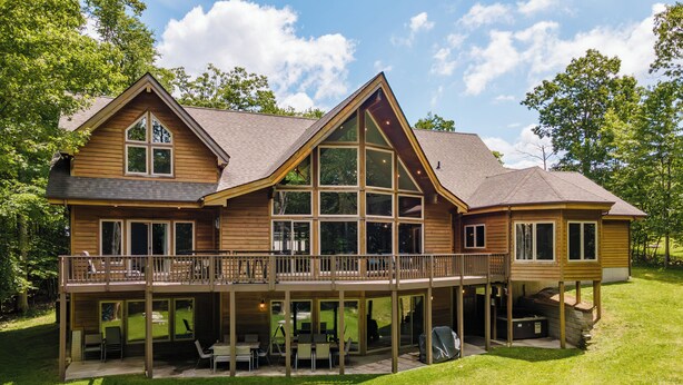 A large wooden house with a balcony and a covered patio area. - Lake Days & Game Nights w/ Hot Tub (Oakland)
