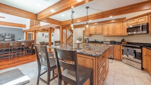 A spacious kitchen with wooden cabinets, a large island, and modern appliances. - Lake Days & Game Nights w/ Hot Tub (Oakland)