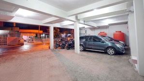 Un estacionamiento con un coche azul y motocicletas aparcadas.
