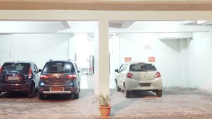 Un edificio con un amplio ventanal y un estacionamiento techado con tres coches.