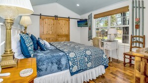 A bedroom with a bed, a vanity, a desk, a chair, a ceiling fan, and a window with a view of the outdoors. - White Rabbit | Amazing Outdoor Area w/ Large Fire Pit | Hot Tub (Fredericksburg)