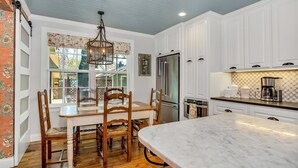 A kitchen with white cabinets, a marble island, a stainless steel refrigerator, and a coffee maker. - White Rabbit | Amazing Outdoor Area w/ Large Fire Pit | Hot Tub (Fredericksburg)