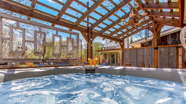 A hot tub area with a wooden pergola overhead, a small building labeled "Pottery," and a view of trees and sky. - White Rabbit | Amazing Outdoor Area w/ Large Fire Pit | Hot Tub (Fredericksburg)