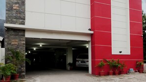 A modern building with a red and white facade, a garage, and several potted plants.