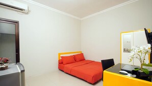 A compact hotel room with a bed, a desk with a laptop, a chair, and a mirror.