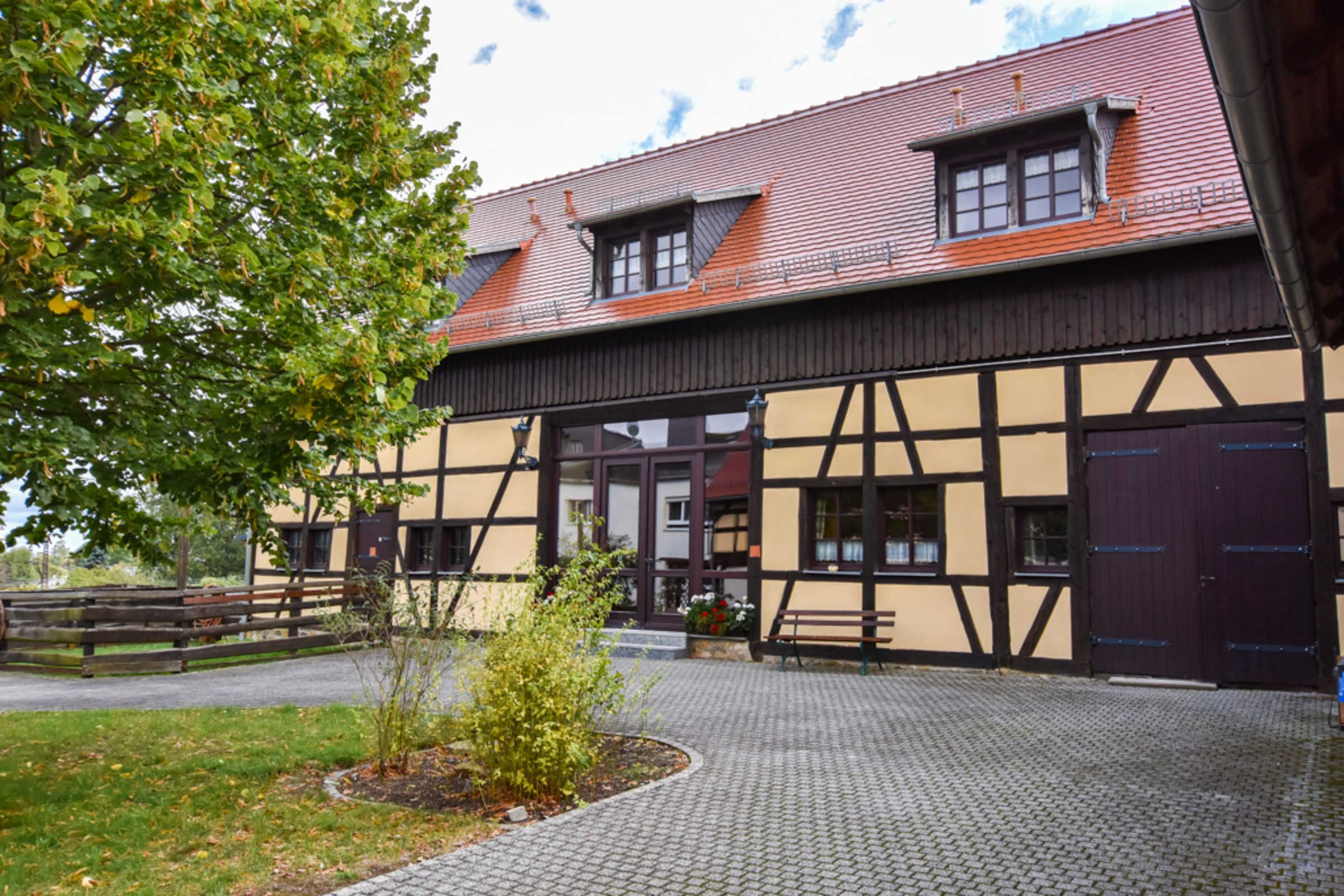 Ein Gebäude mit einer traditionellen Fachwerkausfachung, einem gepflasterten Innenhof und einem Holzzaun.