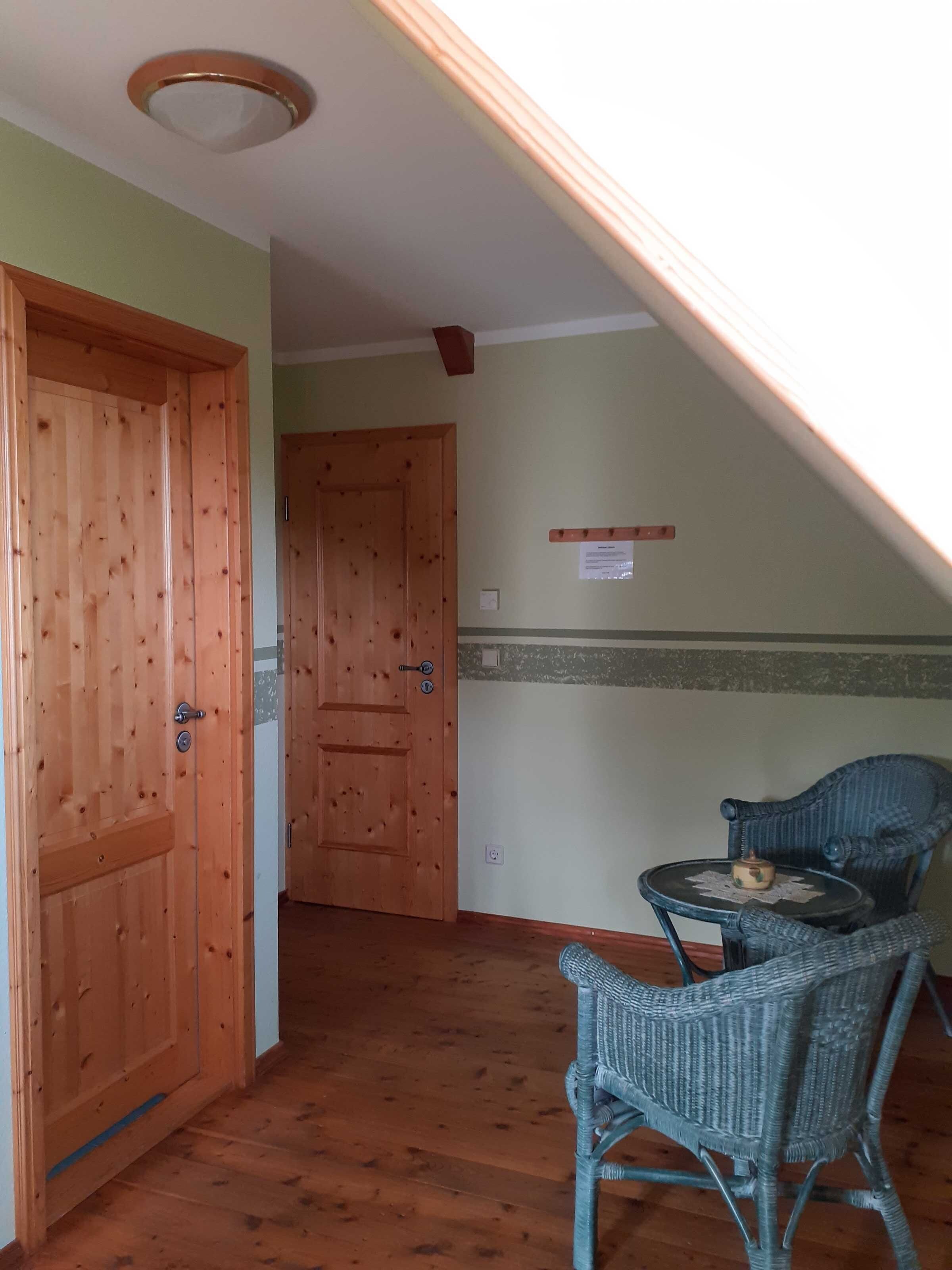 Una habitación con puertas de madera, una mesita con una silla y una lámpara en el techo.