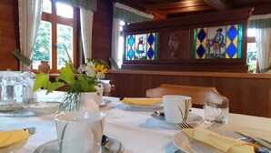 Une table à manger dressée avec des assiettes, des couverts et un vase de fleurs.