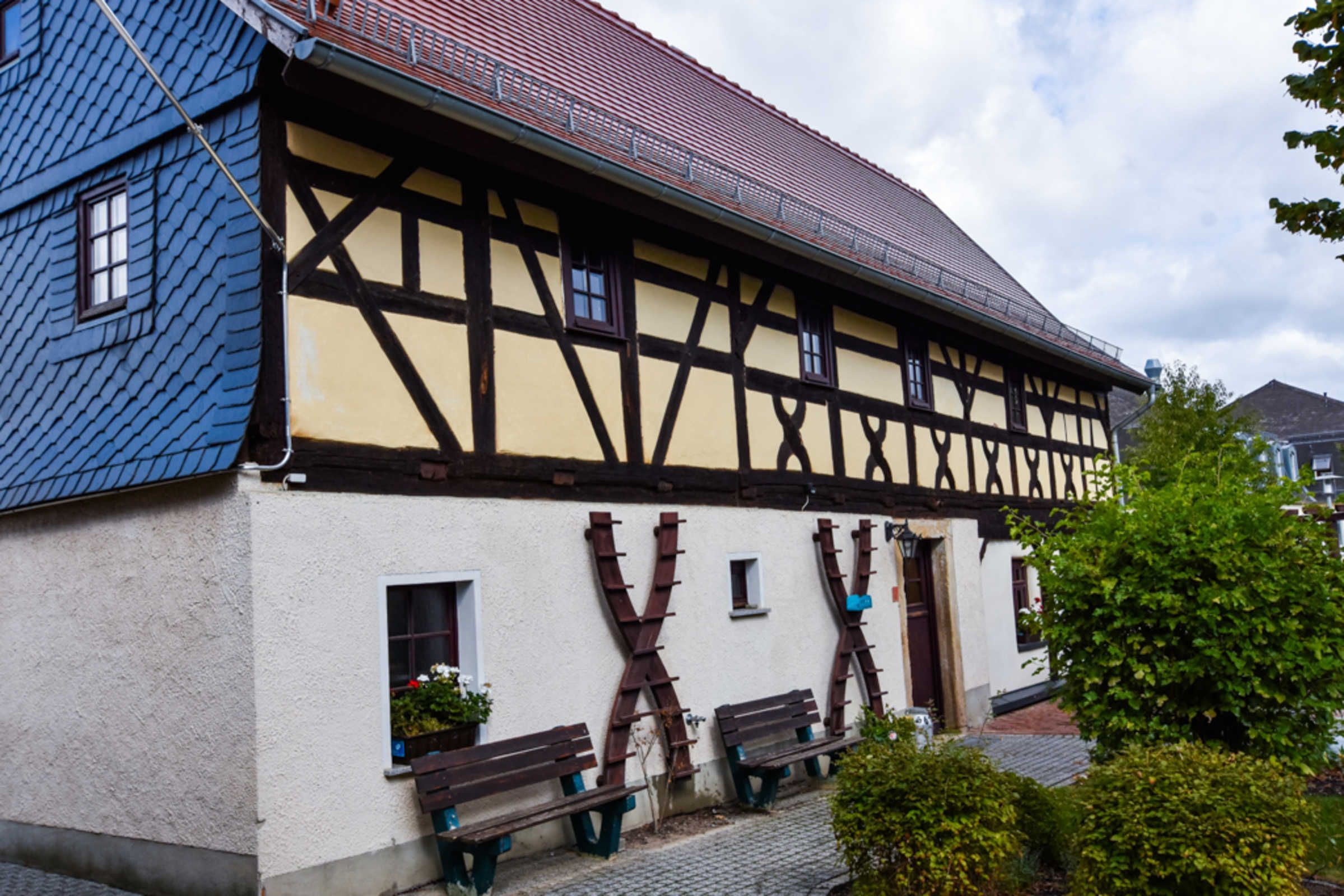 Ein traditionelles Fachwerkhäuschen mit geneigtem Dach, Holzbalken und einer weißen Fassade.