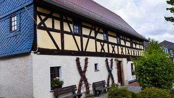 Ein traditionelles Fachwerkhäuschen mit geneigtem Dach, Holzbalken und einer weißen Fassade.