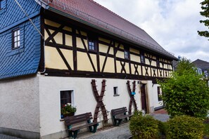 A traditional half-timbered building with a sloped roof, wooden beams, and a white facade.