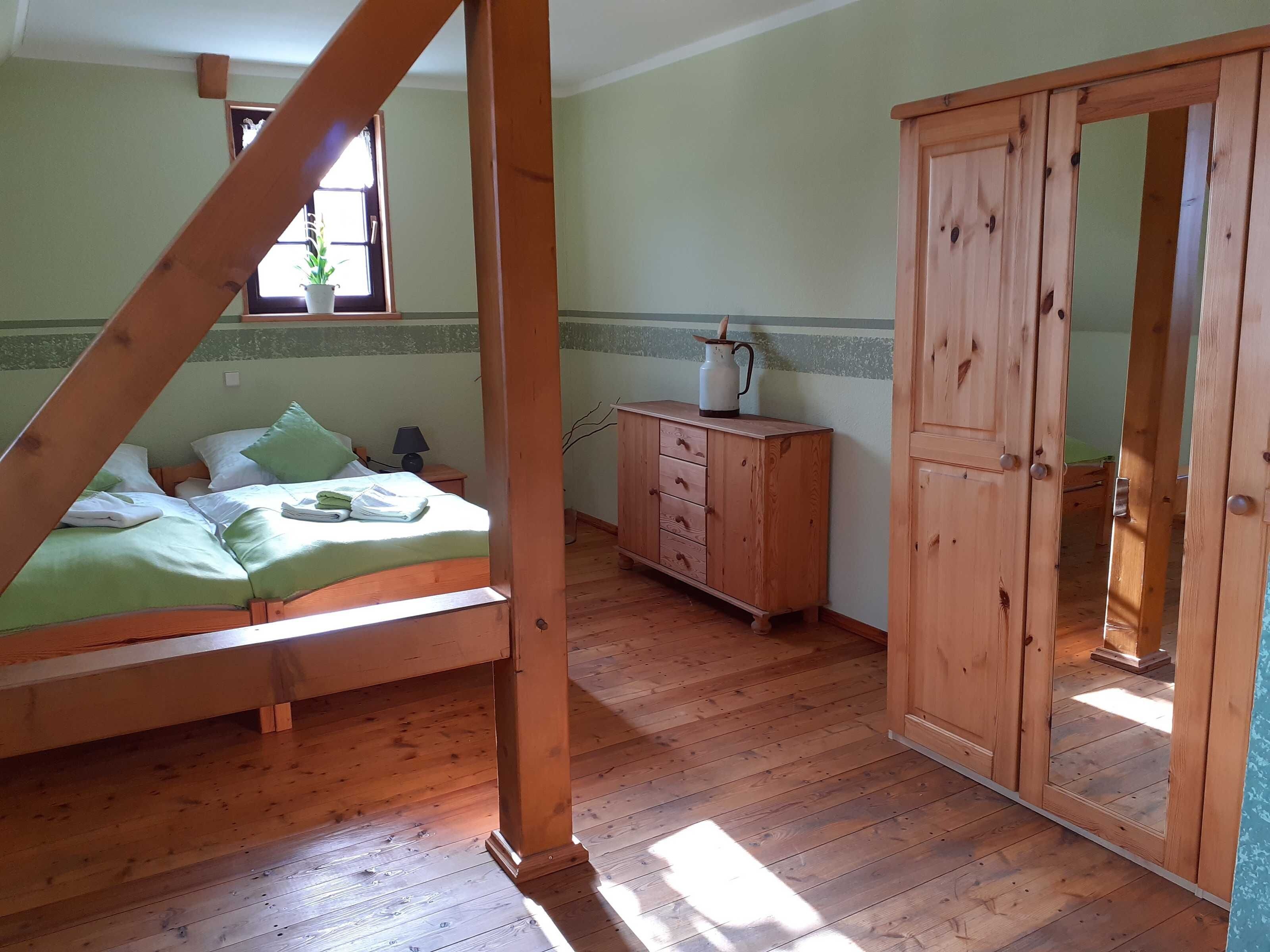 A room with a wooden bed, a dresser, and a wardrobe.