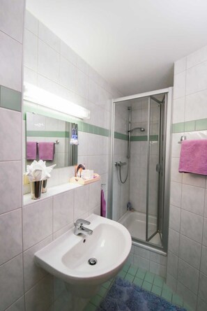 A bathroom with a sink, mirror, shower, and tiled walls. - EZ Gartenblick - Lavendelhof - Die Idyllische Landpension (Crimmitschau)