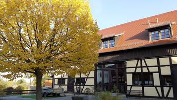 A traditional building with a gabled roof and a large tree with yellow leaves in the foreground.