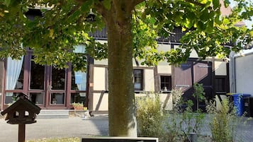 A welcome sign under a tree, a bird feeder, and a building with large windows in the background.