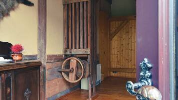 A wooden interior with a rustic door, a wooden floor, and a wall-mounted animal head.