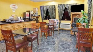 A dining area with a table and chairs, a coffee machine, and a TV on the wall. - Sapphire Inn & Suites- Deer Park (Deer Park)