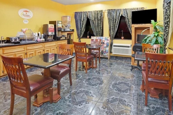 A dining area with a table and chairs, a coffee machine, and a TV on the wall. - Sapphire Inn & Suites- Deer Park (Deer Park)