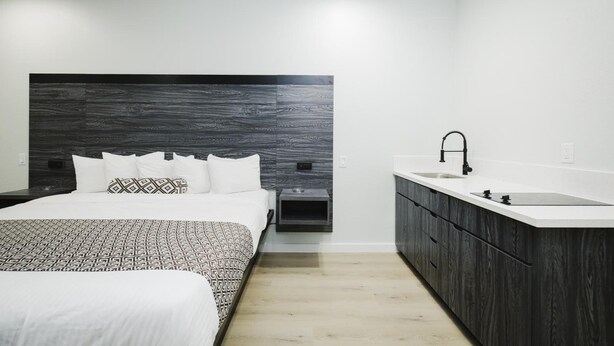 A modern bedroom with a large bed, a bedside table, and a built-in nightstand. - Sapphire Inn & Suites- Deer Park (Deer Park)