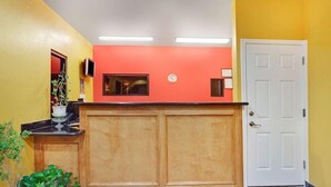 A reception area with a wooden counter, a white door, and a potted plant. - Sapphire Inn & Suites- Deer Park (Deer Park)