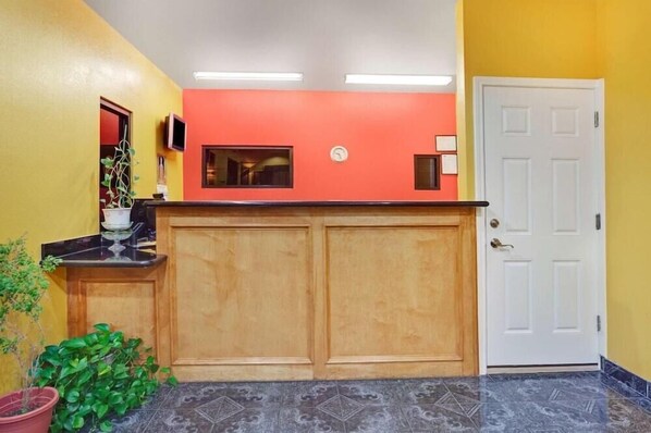 A reception area with a wooden counter, a white door, and a potted plant. - Sapphire Inn & Suites- Deer Park (Deer Park)