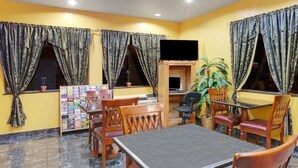 A dining area with a table and chairs, a television, and a bookshelf. - Sapphire Inn & Suites- Deer Park (Deer Park)