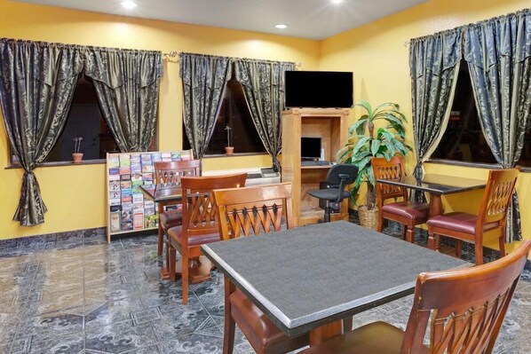 A dining area with a table and chairs, a television, and a bookshelf. - Sapphire Inn & Suites- Deer Park (Deer Park)
